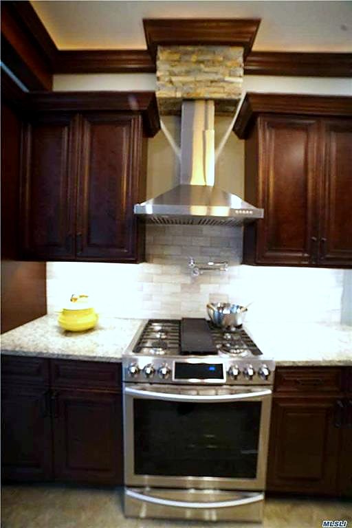Range, stone hood and tile backsplash