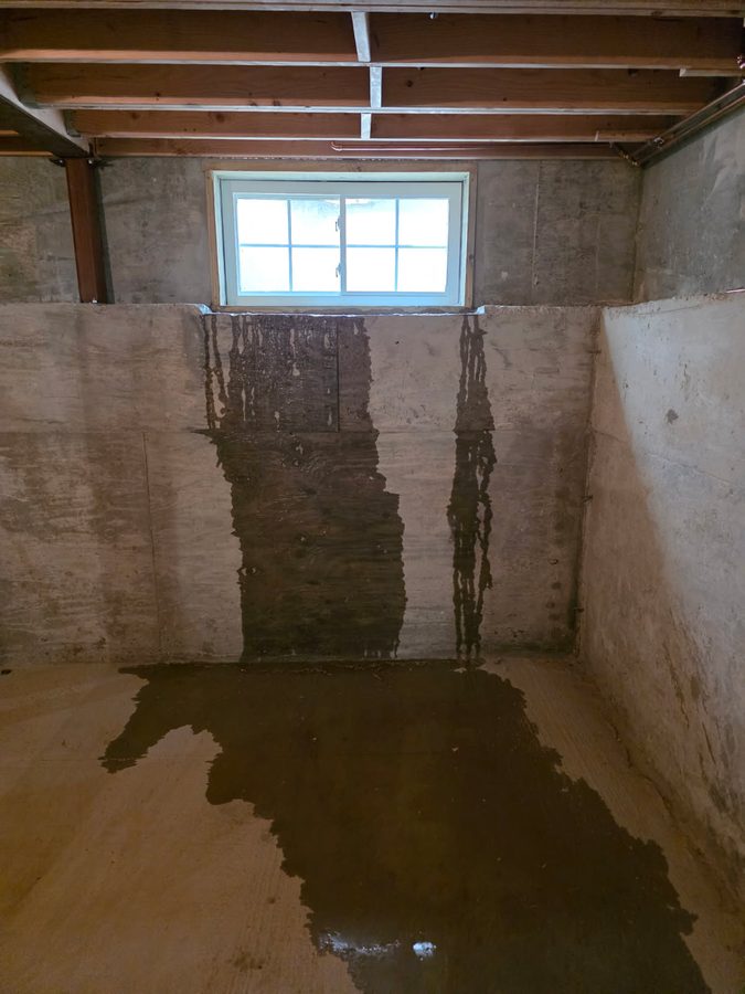 Groundwater pouring in beneath a basement window and pooling on the floor of a Long Island home
